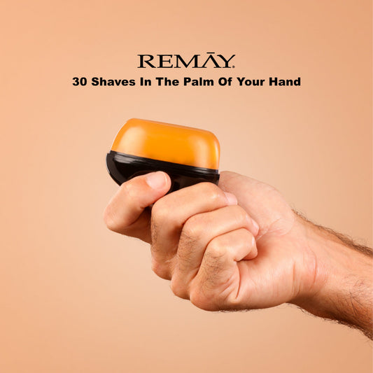 Hand holding a black and orange REMAY shaving cream gel for men with REMAY branding and text on a beige background that reads "30 haves in the palm of your hand"