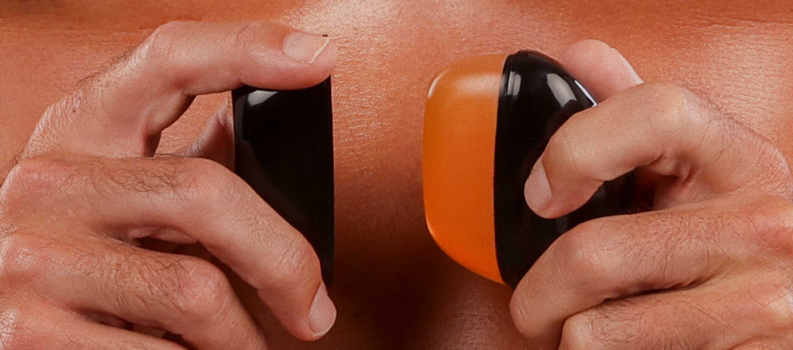 Close-up of a man holding a black and orange REMAY Heat shaving cream for men gel bar near abdomen.