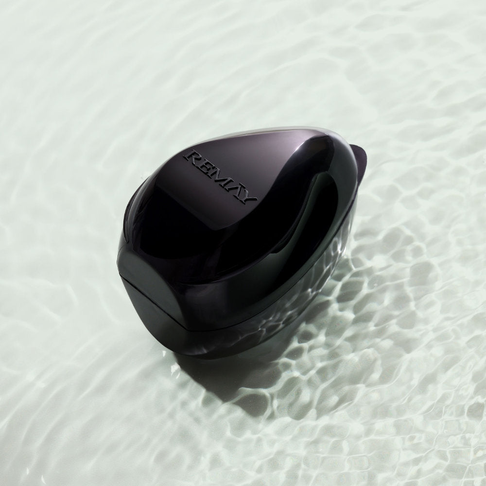 Black REMAY shaving cream gel bar floating in the sand in the ocean.