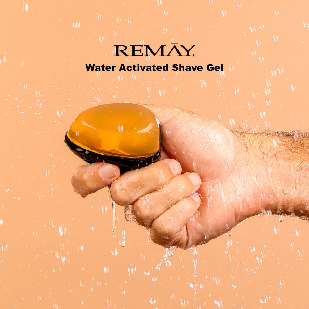 Hand holding an orange and black water activated shaving cream gel for men with REMAY branding on a beige background.